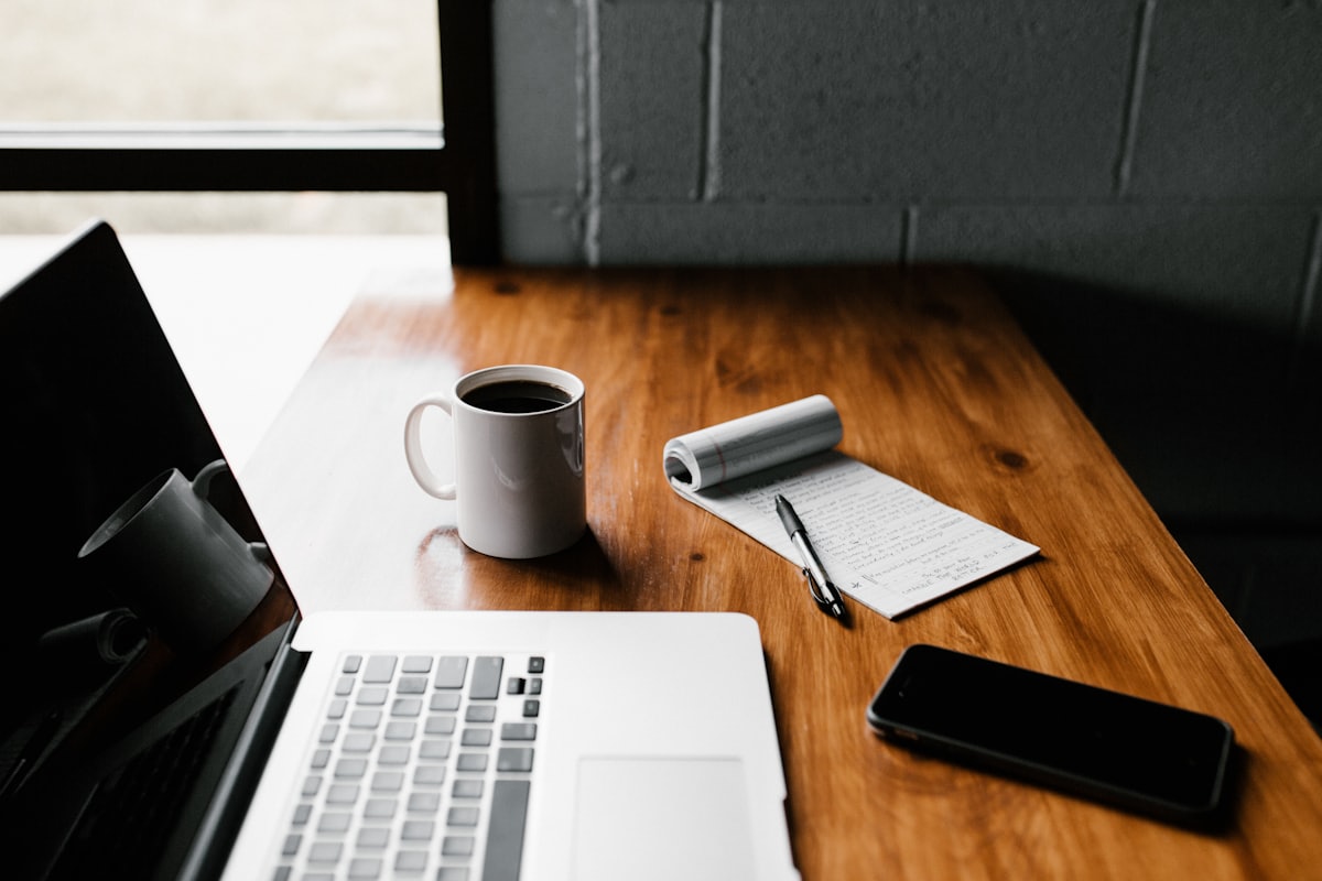 Escritorio con una laptop, una libreta y una taza de café